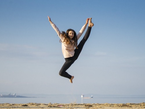 Woman jumping on a beach with blue sky in the background